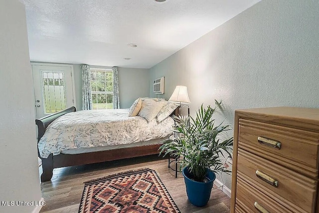 bedroom with a wall mounted air conditioner and dark hardwood / wood-style floors