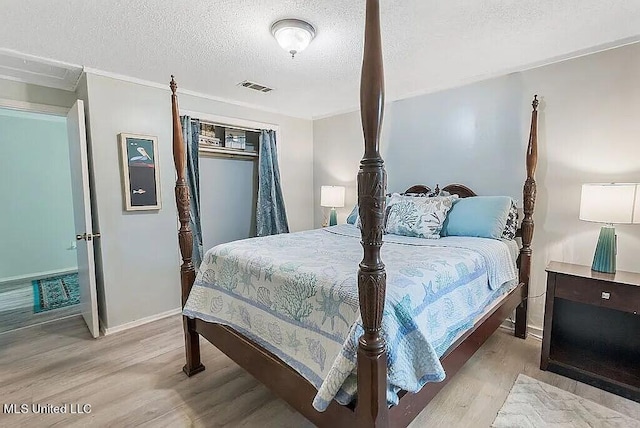 bedroom with light hardwood / wood-style floors and a textured ceiling