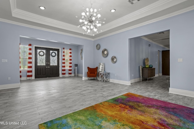 foyer entrance featuring a tray ceiling, wood finished floors, a chandelier, crown molding, and baseboards