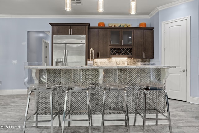 bar area featuring stainless steel built in fridge, backsplash, baseboards, crown molding, and light wood-style floors