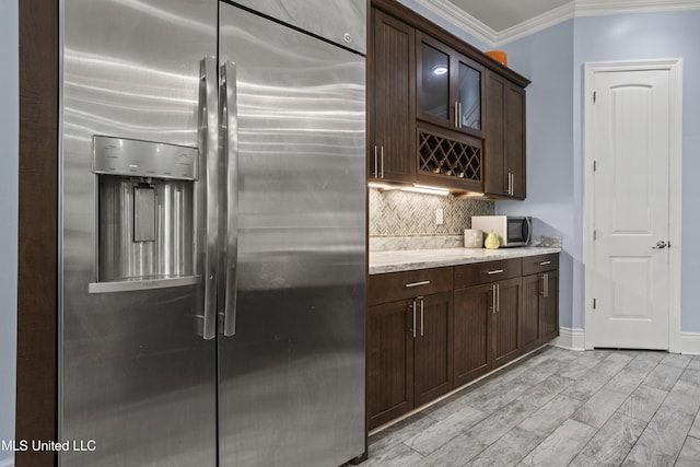 kitchen with appliances with stainless steel finishes, backsplash, dark brown cabinets, crown molding, and light stone counters