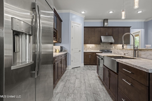 kitchen with appliances with stainless steel finishes, under cabinet range hood, dark brown cabinetry, a sink, and light wood-style flooring