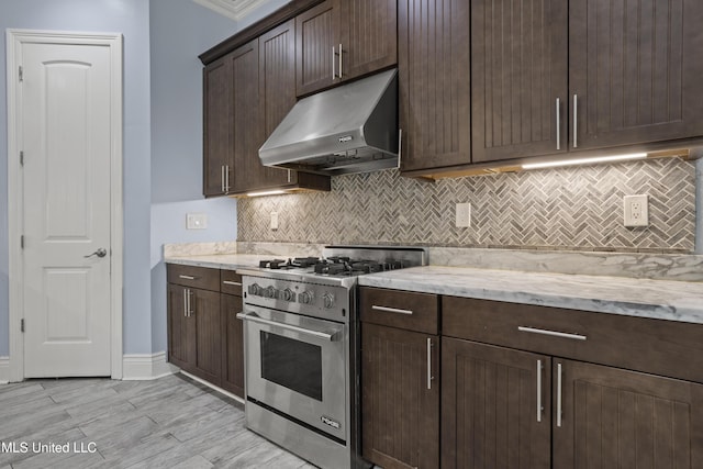 kitchen featuring high end range, under cabinet range hood, backsplash, dark brown cabinetry, and light stone countertops