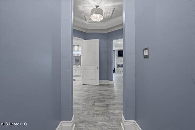corridor featuring ornamental molding, a chandelier, and baseboards