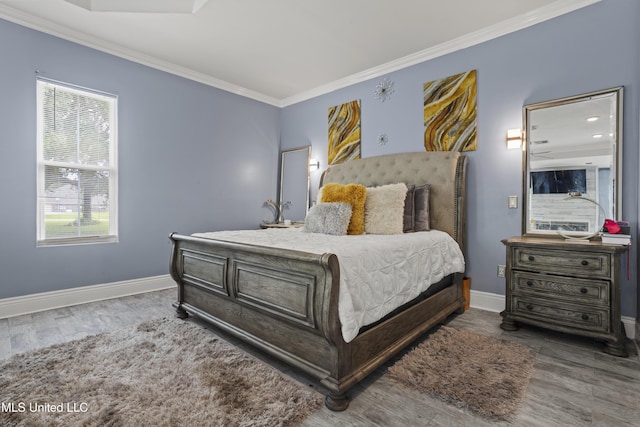 bedroom featuring baseboards, wood finished floors, and ornamental molding