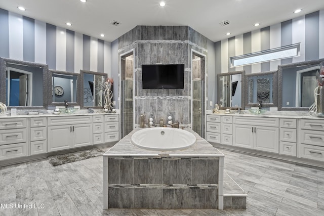 full bath featuring a garden tub, two vanities, and recessed lighting