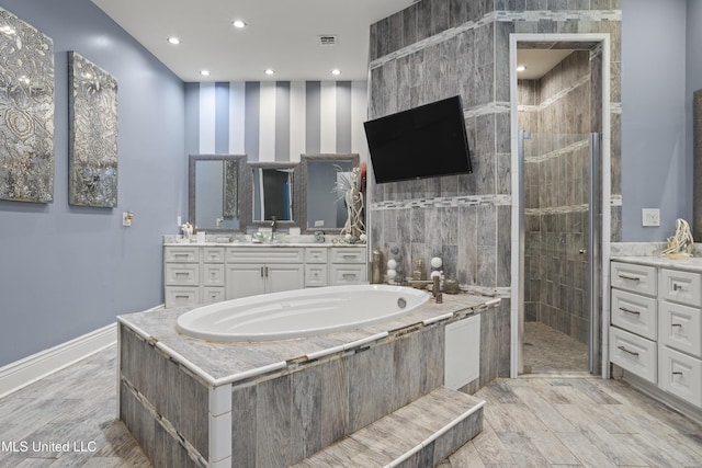 bathroom with tiled shower, a garden tub, vanity, wood finished floors, and recessed lighting