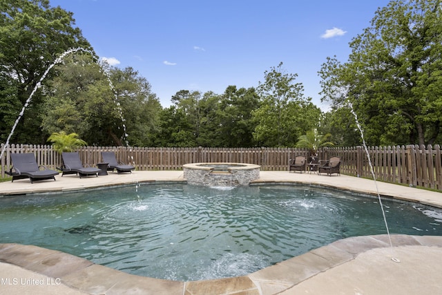 view of swimming pool featuring fence, a patio, a pool with connected hot tub, and view of scattered trees