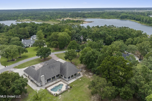 bird's eye view of a heavily wooded area, a nearby body of water, and a pool