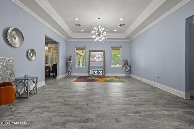 foyer with a tray ceiling, a chandelier, wood finished floors, baseboards, and ornamental molding