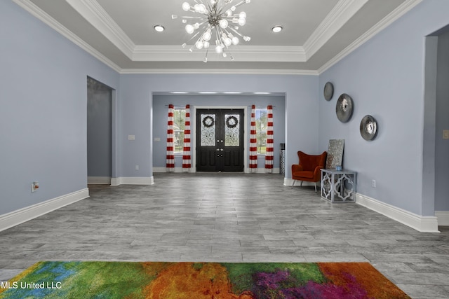 entrance foyer featuring wood finished floors, a raised ceiling, a chandelier, and ornamental molding