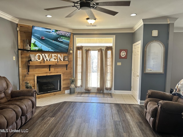 living room featuring crown molding, light hardwood / wood-style flooring, a large fireplace, and ceiling fan