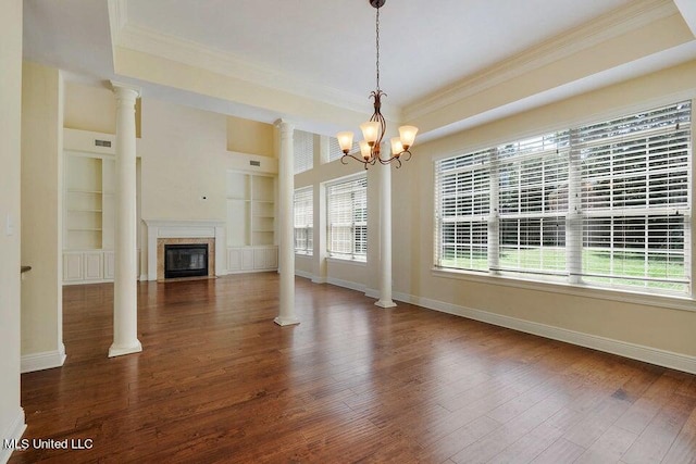 unfurnished living room featuring ornamental molding, dark wood-type flooring, built in shelves, and decorative columns