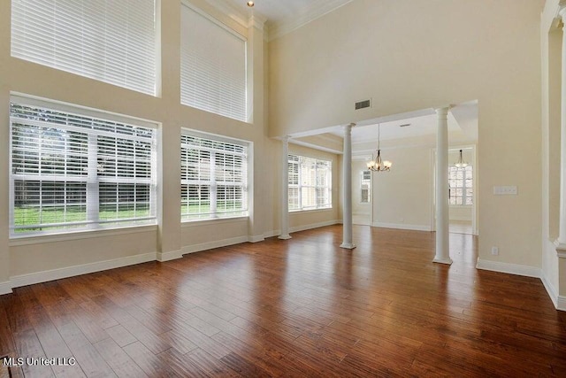 unfurnished living room with ornate columns, crown molding, wood-type flooring, and a high ceiling