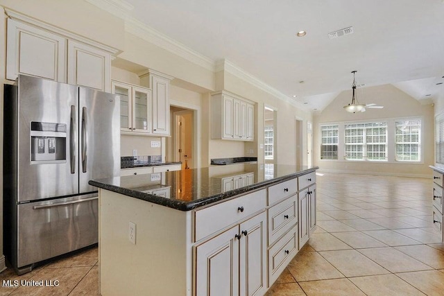 kitchen featuring light tile patterned floors, a kitchen island, dark stone counters, ornamental molding, and stainless steel refrigerator with ice dispenser