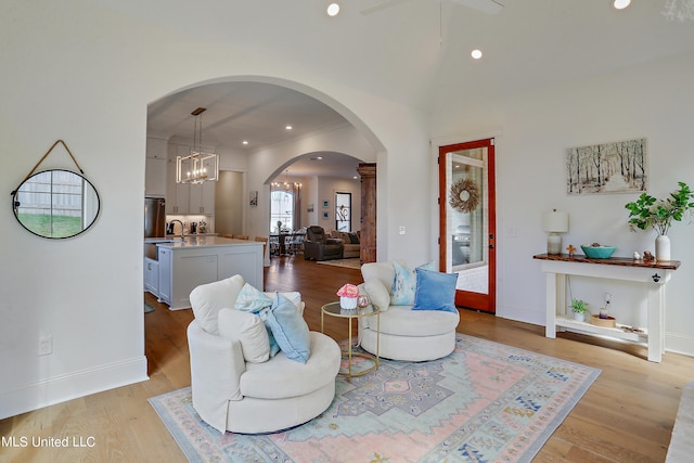 living room with an inviting chandelier, sink, and light hardwood / wood-style flooring