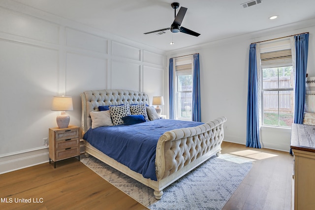 bedroom with hardwood / wood-style floors, ornamental molding, and ceiling fan