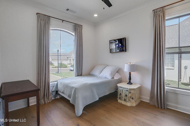 bedroom with wood-type flooring, ornamental molding, and ceiling fan