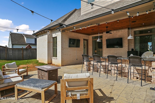 view of patio / terrace featuring a bar, ceiling fan, and an outdoor living space