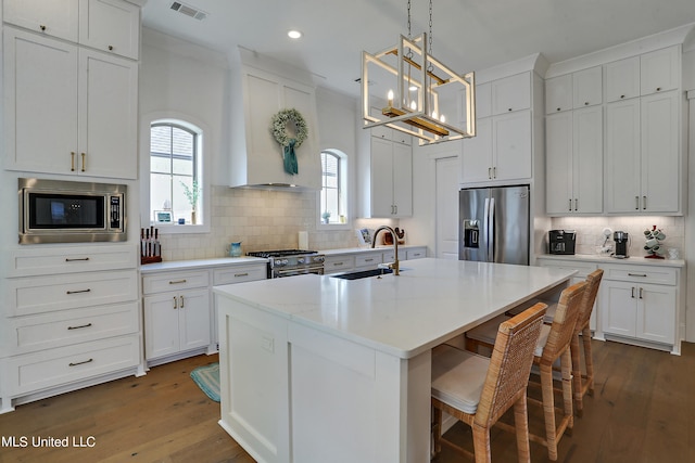 kitchen with sink, stainless steel appliances, an island with sink, and white cabinets