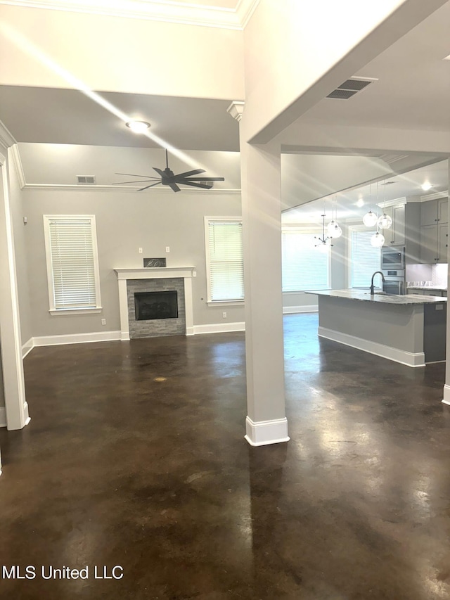 unfurnished living room featuring ceiling fan, ornamental molding, and sink