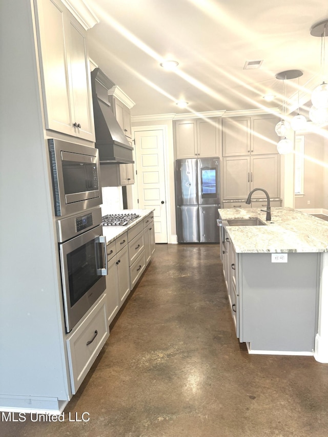 kitchen featuring a center island with sink, appliances with stainless steel finishes, custom range hood, sink, and decorative light fixtures