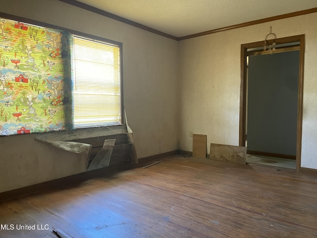 unfurnished room with a textured ceiling, wood finished floors, visible vents, and ornamental molding