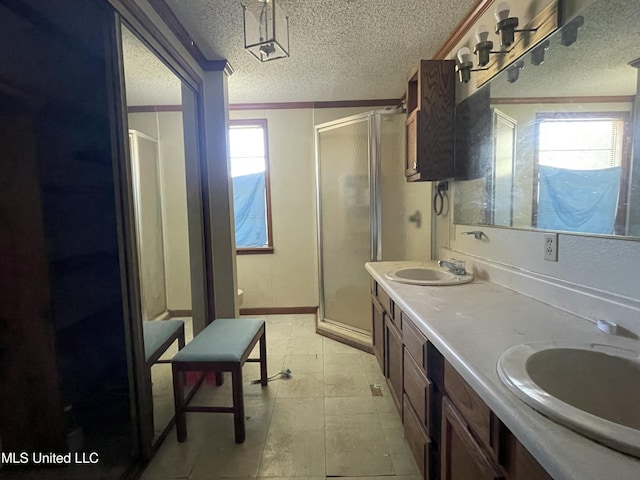 full bath with a shower stall, a textured ceiling, and a sink