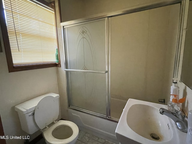 full bath featuring toilet, bath / shower combo with glass door, and a sink