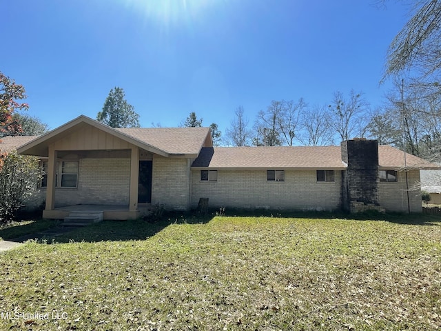 single story home featuring brick siding, covered porch, a front yard, and roof with shingles