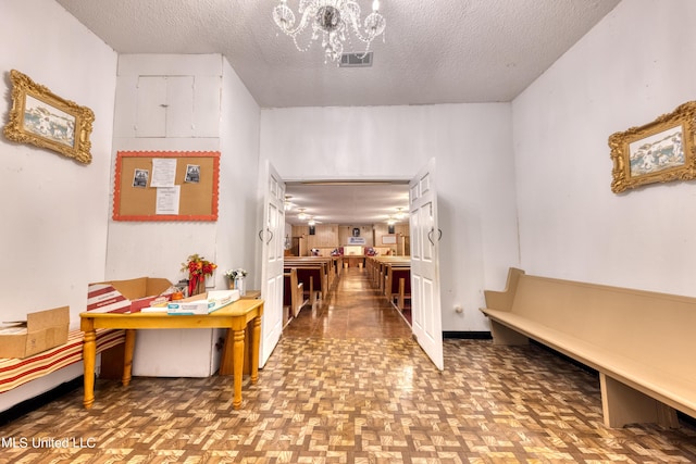 hall featuring a chandelier, visible vents, and a textured ceiling