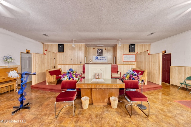 game room with wooden walls, a textured ceiling, and tile patterned floors