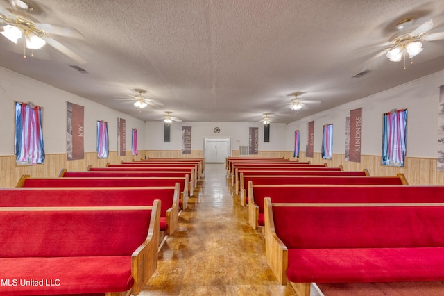 misc room with wainscoting, a textured ceiling, and concrete flooring