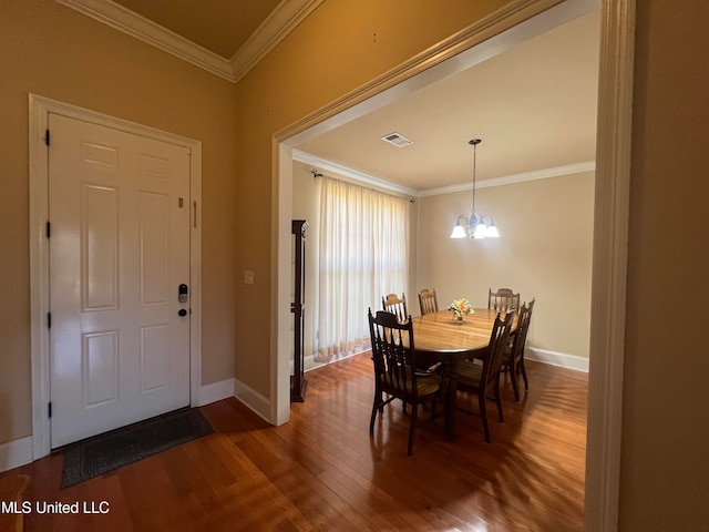 dining area with dark wood-type flooring, a notable chandelier, and crown molding