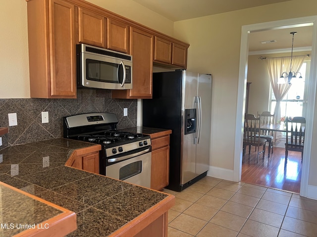 kitchen with light tile patterned flooring, crown molding, decorative backsplash, and stainless steel appliances