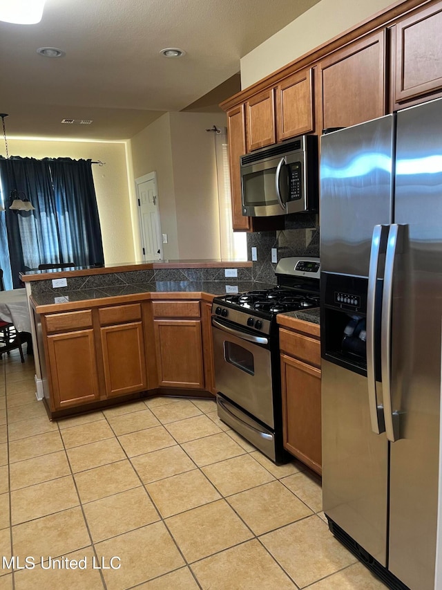 kitchen featuring light tile patterned flooring, kitchen peninsula, tasteful backsplash, and stainless steel appliances