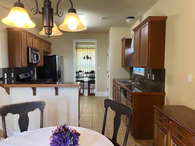 kitchen featuring appliances with stainless steel finishes, sink, decorative light fixtures, decorative backsplash, and light tile patterned floors