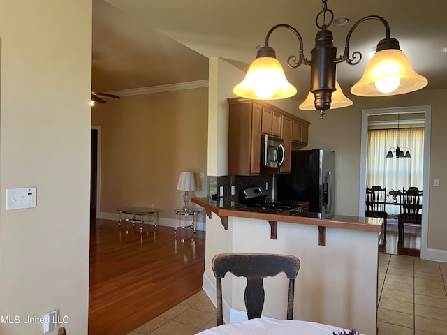 kitchen featuring a kitchen breakfast bar, pendant lighting, light tile patterned floors, appliances with stainless steel finishes, and tasteful backsplash