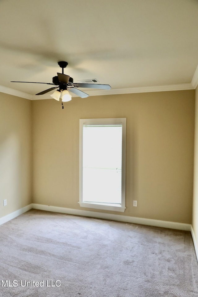 carpeted spare room featuring ornamental molding, baseboards, and a ceiling fan