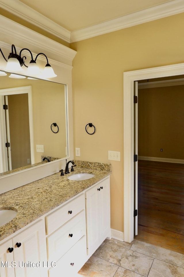 bathroom featuring baseboards, ornamental molding, double vanity, and a sink