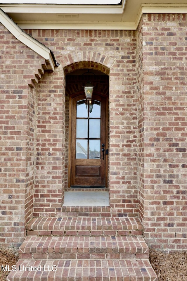entrance to property featuring brick siding
