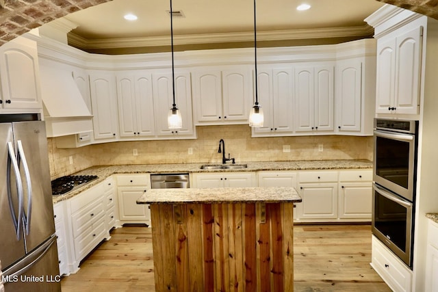 kitchen with a sink, stainless steel appliances, decorative light fixtures, light wood-style floors, and decorative backsplash