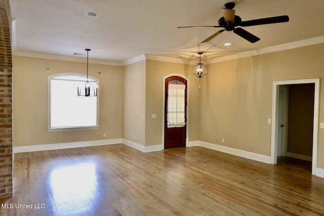 empty room with visible vents, ceiling fan, crown molding, wood finished floors, and arched walkways