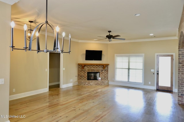 unfurnished living room with baseboards, a brick fireplace, wood finished floors, and ceiling fan with notable chandelier