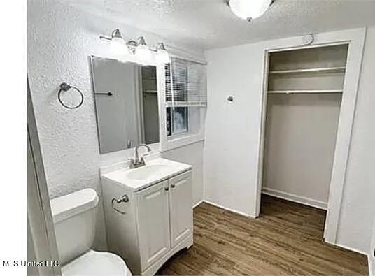 1325 Fourth Ave, Jackson, MS 39209 - bathroom featuring wood finished floors, a textured wall, toilet, vanity, and a textured ceiling