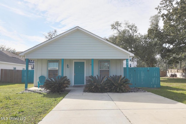 bungalow with a front lawn, board and batten siding, and fence