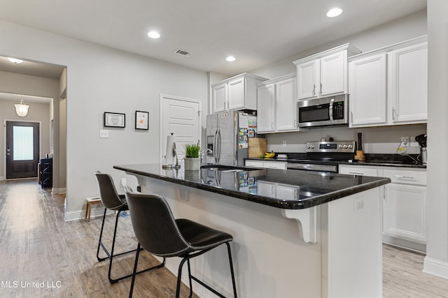 kitchen with stainless steel appliances, a kitchen breakfast bar, and a kitchen island with sink