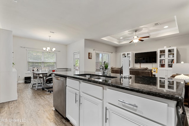 kitchen featuring dark stone countertops, a raised ceiling, light hardwood / wood-style flooring, white cabinets, and pendant lighting