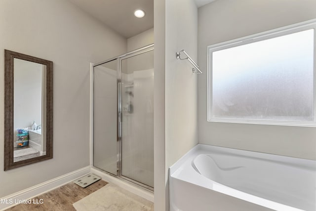 bathroom with shower with separate bathtub and wood-type flooring