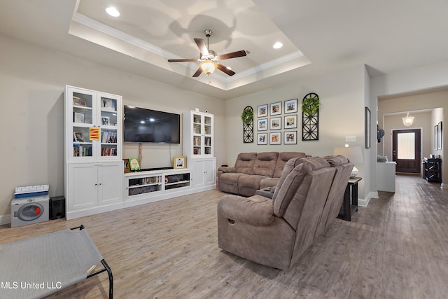 living room with ornamental molding, hardwood / wood-style flooring, a raised ceiling, and ceiling fan